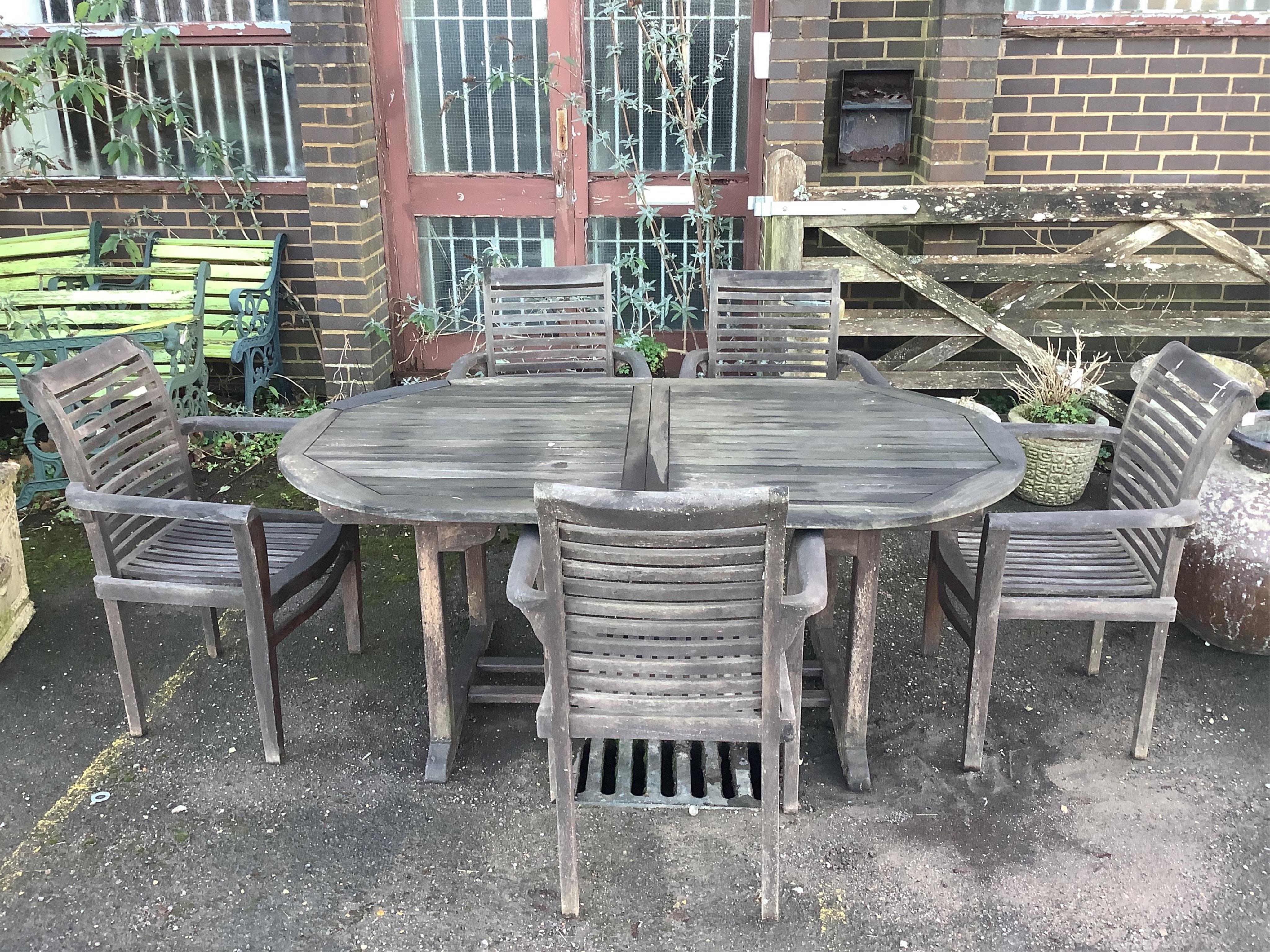 A teak extending garden table, width 180cm, depth 100cm, height 75cm, and five elbow chairs. Condition - fair